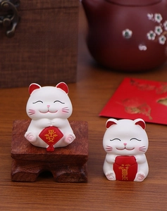 Detail of two mini resin fortune cats featuring Pingan and Xile lucky messages