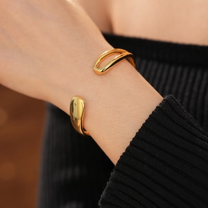 Detailed close-up of gold-plated waterdrop open bangle on a model's wrist