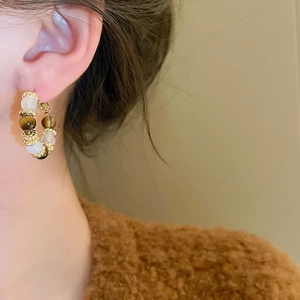 Close-up of vintage beaded hoop earrings with tiger eye stone on a female model