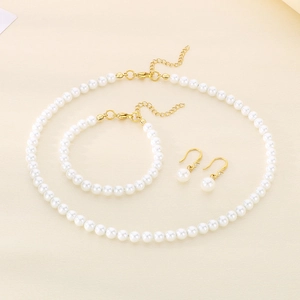 Flat lay of elegant white pearl jewelry set with golden metal clasps on a soft beige surface