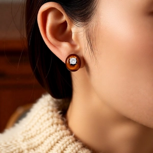 Close-up of a vintage oval stud earring with clear zircon and amber resin on a model ear