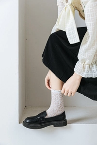 Detail of white mesh lace socks featuring elegant ruffled edges on a model