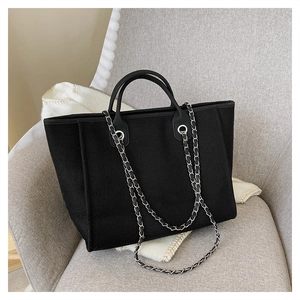 Detail of black woven tote bag with silver chain strap and premium leather handles
