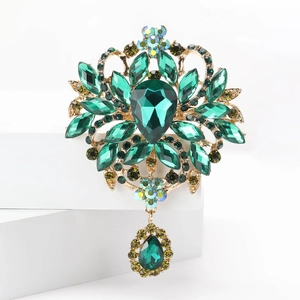 Gros plan d'une grande broche en strass vert avec cristaux jaunes et finition dorée