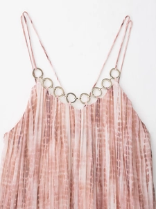 Primer plano de un vestido plisado tie-dye rosa con detalles de anillos de metal