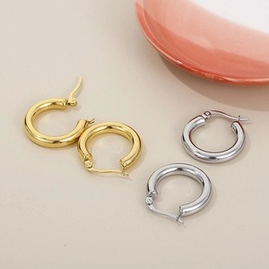 Top view of gold and silver solid stainless steel hoop earrings on minimalist background