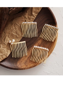 Detailed close-up of gold hair combs with pearls and rhinestones on a wooden tray