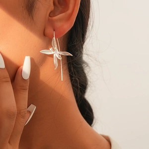 Close-up of elegant silver iris flower earrings worn by a model in warm light