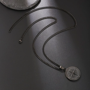 Close-up of a matte black compass coin pendant on a thick curb chain for men