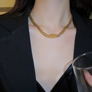 Close-up of gold chunky chain necklace featuring a classic CD letter design on a model