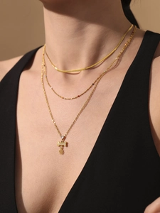 Detail van gelaagde gouden ketting met een bot hanger van strass en hartvormig slotje
