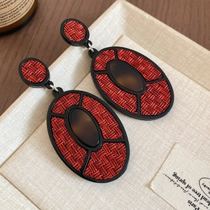 Macro shot of vintage oval earrings with red woven texture and brown resin detail