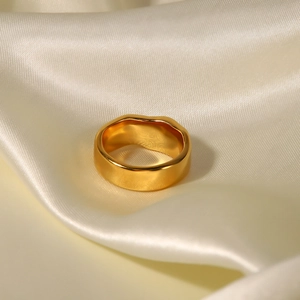 Detail of 18K gold plated lava texture ring on premium beige silk fabric background