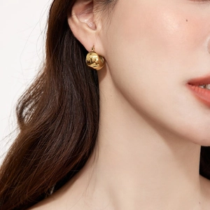Detail of chunky gold drop earring with mirror finish on model with minimalist aesthetic