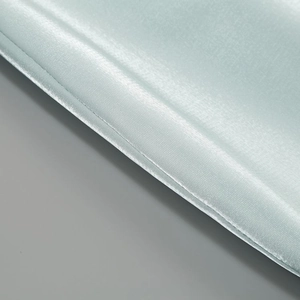 Detail of light blue satin dress fabric showing smooth texture and fine stitching