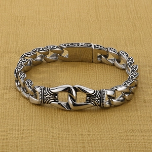 Detailed close-up of retro silver totem engraved links on a heavy Cuban steel bracelet