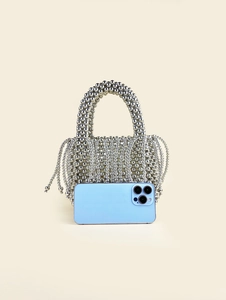 Silver beaded handmade mini basket bag with curved handle showing size next to a smartphone