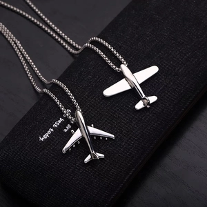 Detail of silver airplane pendants with box chains on a black jewelry gift box