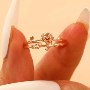 Close-up of elegant rose gold double-ring with blooming rose and leaf detailing