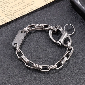 Detail of vintage silver-tone steel chain bracelet with industrial hook clasp on black leather