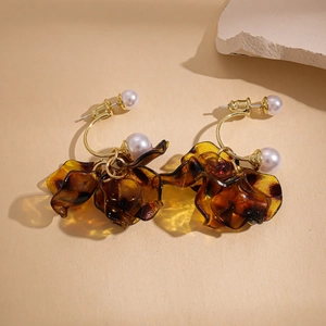 Detail of amber acrylic flower petal earrings with white pearls and gold hardware