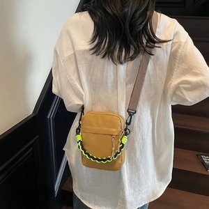 Back view of mustard yellow canvas crossbody bag with contrast green woven handle
