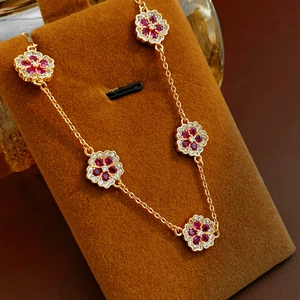 Detail of 18k gold plated flower bracelet featuring red zircon and white stones