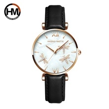 Detail of rose gold watch case with golden dragonfly motifs and black leather strap