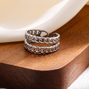 Macro shot of double-layer silver Cuban link chain ring on white silk background
