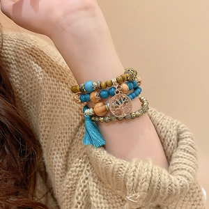 Detail of multi-layer sandalwood bead bracelet with Tree of Life charm and blue tassel