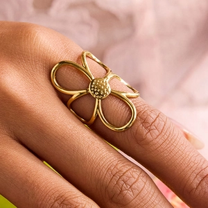 Close-up of a gold floral ring featuring a hollow petal design on a model's finger
