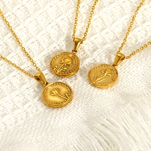 Three gold lily of the valley flower coin pendant necklaces on white knit fabric background