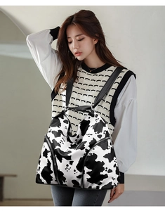 Close-up of stylish cow print backpack on model with black straps and zip detail