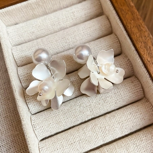 Macro shot of silver flower earrings with pearls and mother-of-pearl petals in a jewelry box