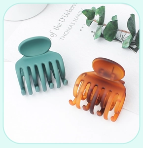Close-up of small matte green and amber tortoiseshell hair claws on a book
