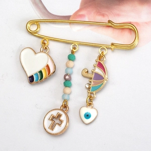 Detailed close-up of a gold safety pin brooch with colorful enamel evil eye charms