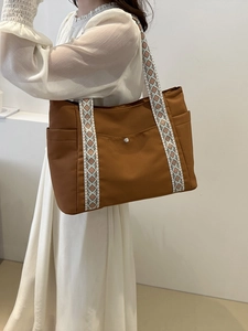 Borsa tote in tela marrone con tracolla a motivo etnico mostrata in ambiente minimalista