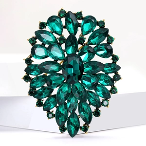 Green crystal brooch with vintage sunburst design and pear-cut stones on white background