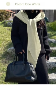 Detail of rice white knitted scarf layered with black ribbed sweater for winter warmth