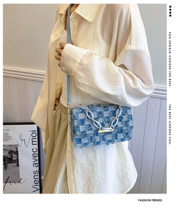 Détail du sac bandoulière en denim à carreaux bleus avec franges et chaîne sur modèle