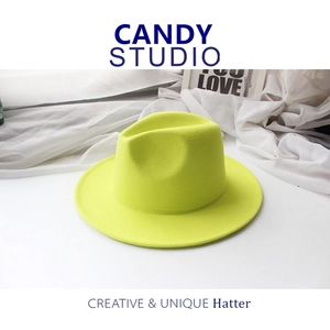 Flat lay of neon yellow wool fedora hat with wide brim on white fabric background