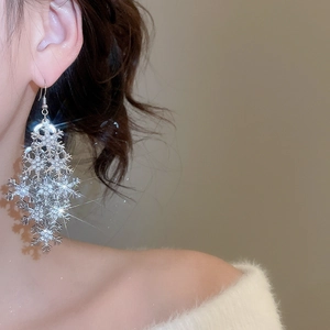Macro detail of silver snowflake tassel earrings with shimmering crystals on model