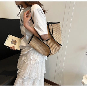 Detail of large capacity straw tote bag with black contrast trim shown with model