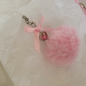 Detail of pink faux fur pompom with a silk bow and a heart-shaped metal pendant