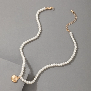 Detail of a pearl necklace featuring a gold shell pendant and adjustable lobster clasp