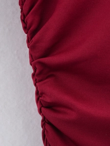 Detail of dark red knitted fabric featuring side ruching and pleated stitching craftsmanship