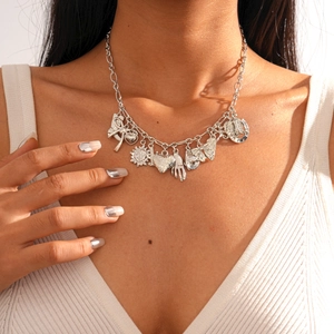 Close-up of silver metal necklace with sun, heart and butterfly charms on a model