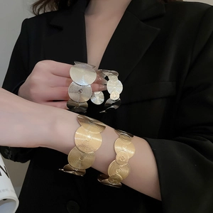 Detail of gold and silver geometric open cuffs with radiant concentric textures