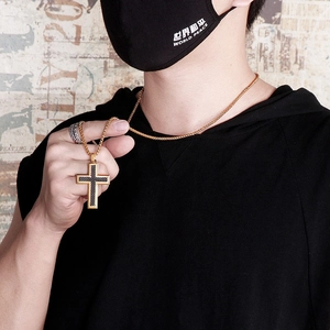 Detailed close-up of a gold cross pendant necklace with black carbon fiber inlay for men