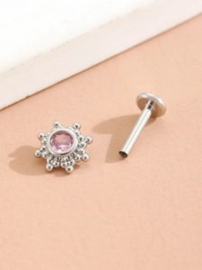 Macro shot of silver labret piercing with a pink gemstone and beaded metal border